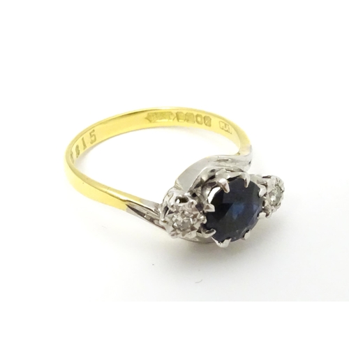 634 - An 18ct gold ring with platinum set central sapphire flanked by two diamonds. Ring size approx. M 1/... 