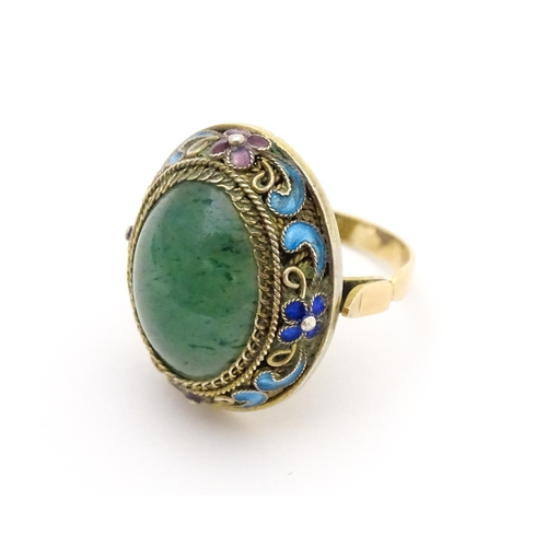 638 - A 14ct gold ring set with central jadeite cabochon  bordered by floral enamel detail. Ring size appr... 