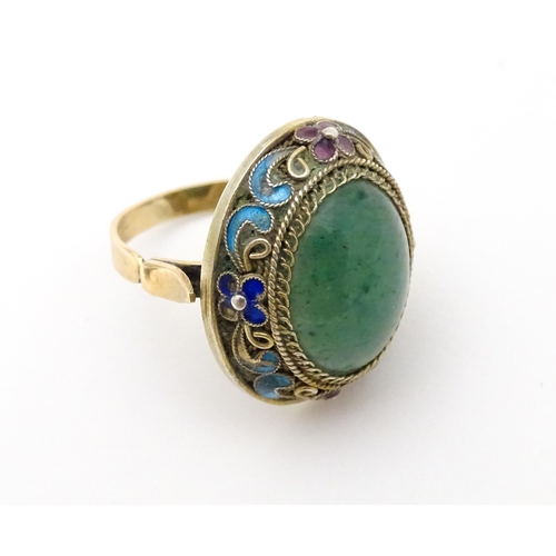 638 - A 14ct gold ring set with central jadeite cabochon  bordered by floral enamel detail. Ring size appr... 