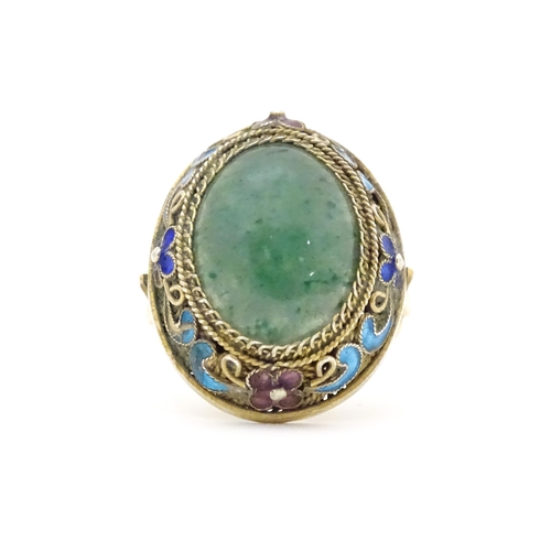 638 - A 14ct gold ring set with central jadeite cabochon  bordered by floral enamel detail. Ring size appr... 