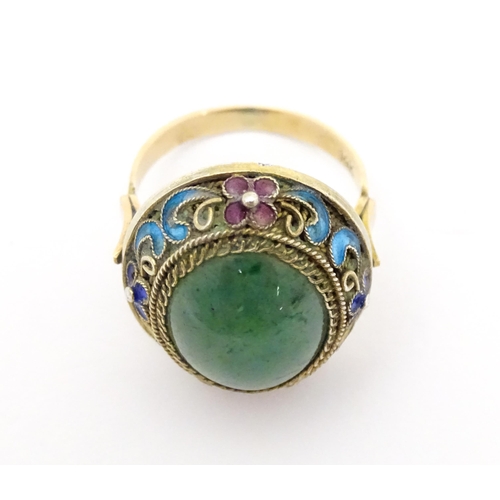 638 - A 14ct gold ring set with central jadeite cabochon  bordered by floral enamel detail. Ring size appr... 