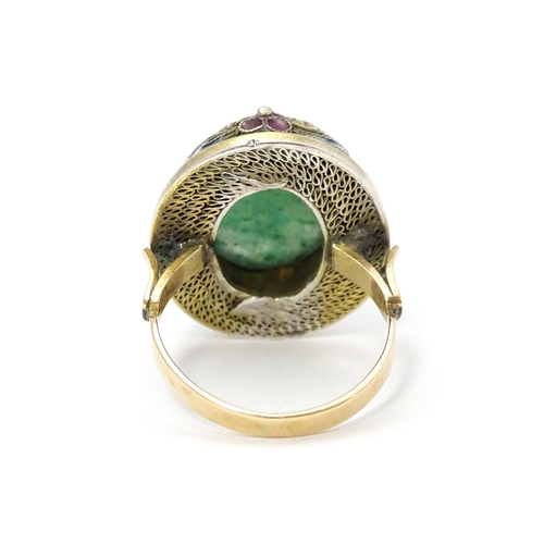 638 - A 14ct gold ring set with central jadeite cabochon  bordered by floral enamel detail. Ring size appr... 