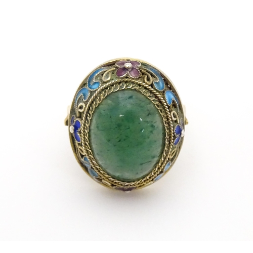 638 - A 14ct gold ring set with central jadeite cabochon  bordered by floral enamel detail. Ring size appr... 