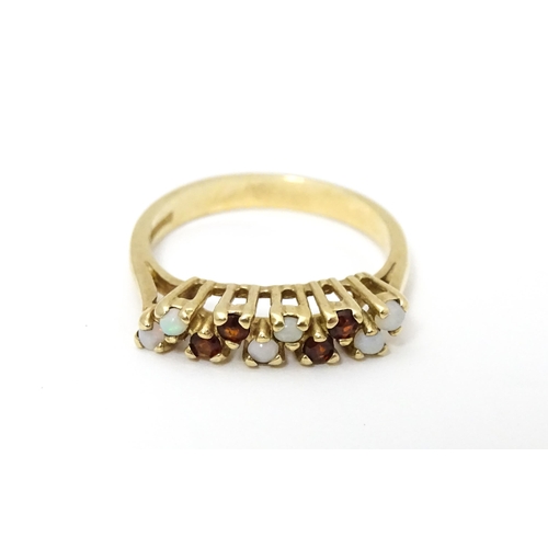 639 - A 9ct gold ring set with opals and garnets. Ring size approx. M