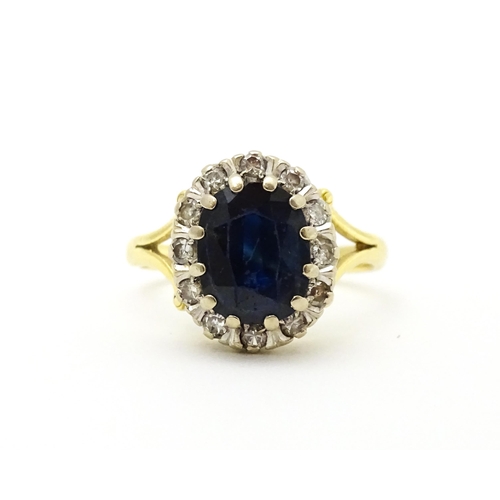 640 - An 18ct gold ring set with central sapphire bordered by diamonds. Ring size approx. L 1/2