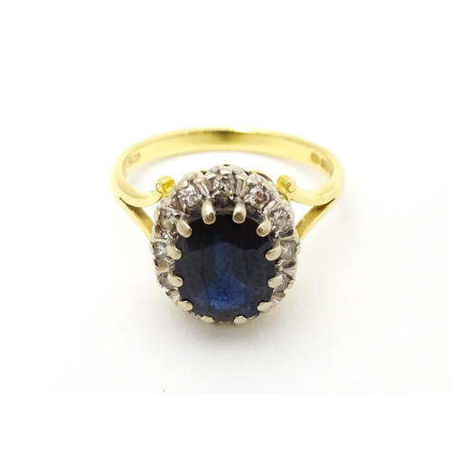 640 - An 18ct gold ring set with central sapphire bordered by diamonds. Ring size approx. L 1/2