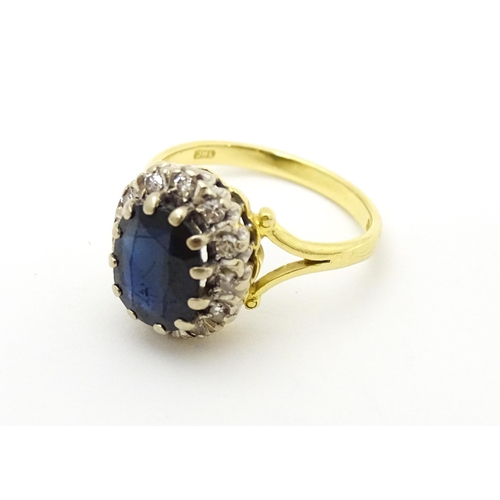 640 - An 18ct gold ring set with central sapphire bordered by diamonds. Ring size approx. L 1/2