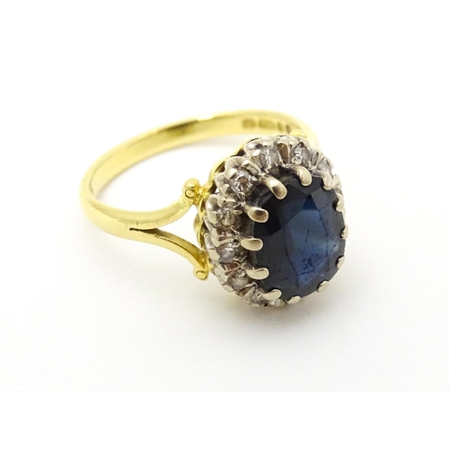 640 - An 18ct gold ring set with central sapphire bordered by diamonds. Ring size approx. L 1/2