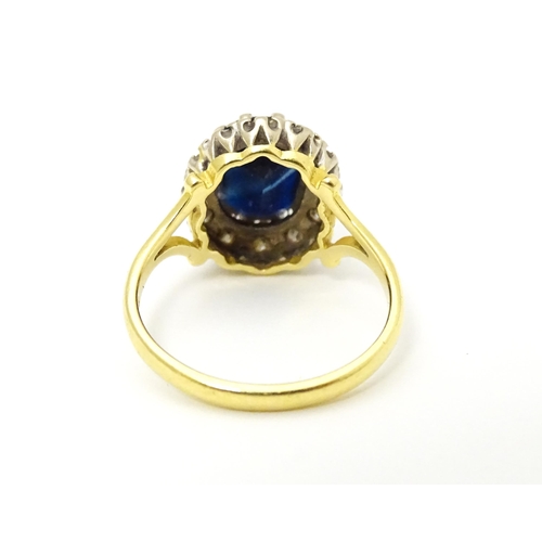 640 - An 18ct gold ring set with central sapphire bordered by diamonds. Ring size approx. L 1/2