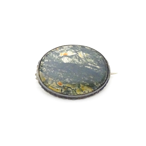 657 - A white metal brooch set with central moss agate cabochon. Approx. 1