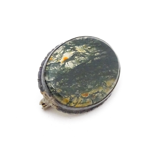 657 - A white metal brooch set with central moss agate cabochon. Approx. 1