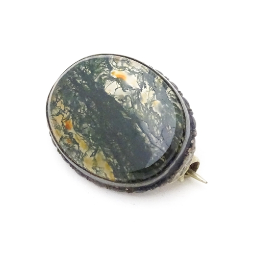 657 - A white metal brooch set with central moss agate cabochon. Approx. 1