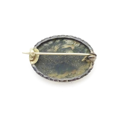 657 - A white metal brooch set with central moss agate cabochon. Approx. 1