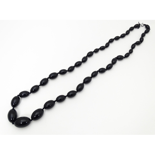 696 - A vintage graduated black amber coloured bead necklace. Approx. 30