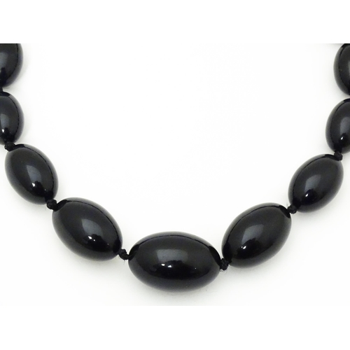 696 - A vintage graduated black amber coloured bead necklace. Approx. 30