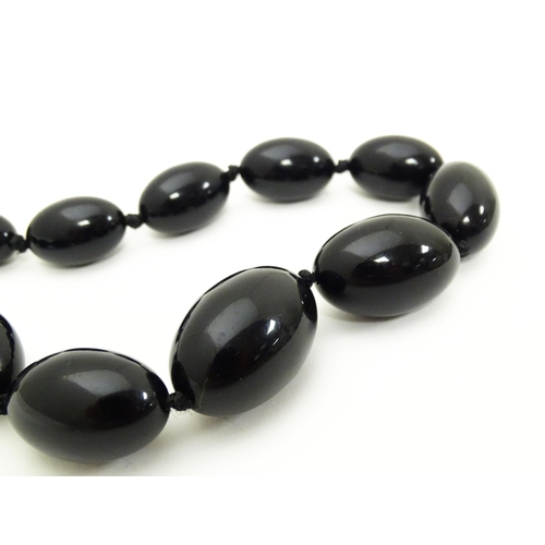 696 - A vintage graduated black amber coloured bead necklace. Approx. 30