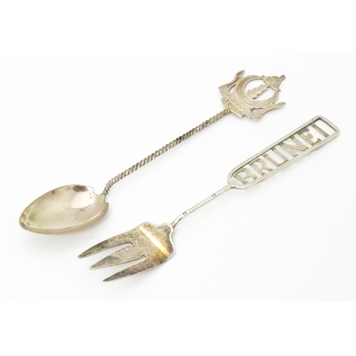 457 - A white metal souvenir fork titled Brunei to handle. Together with a white metal teaspoon also title... 