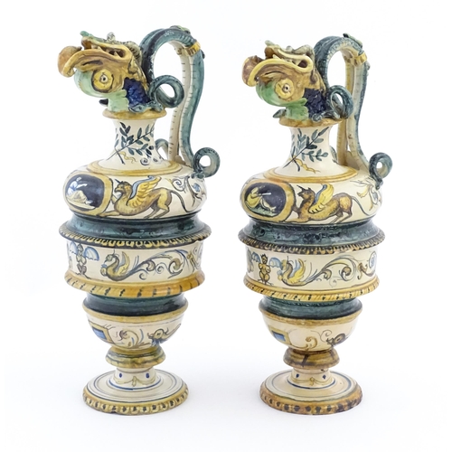 174 - A pair of Italian maiolica wine ewers with fish head spouts, scrolling handles and relief mask detai... 