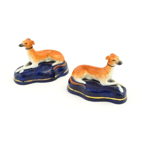 75 - A pair of Staffordshire pottery models of reclining greyhounds / dogs. Approx. 3 1/2