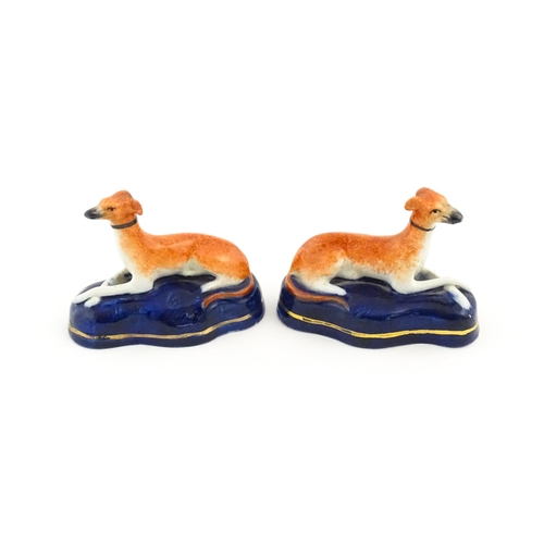 75 - A pair of Staffordshire pottery models of reclining greyhounds / dogs. Approx. 3 1/2