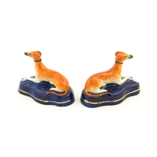 75 - A pair of Staffordshire pottery models of reclining greyhounds / dogs. Approx. 3 1/2