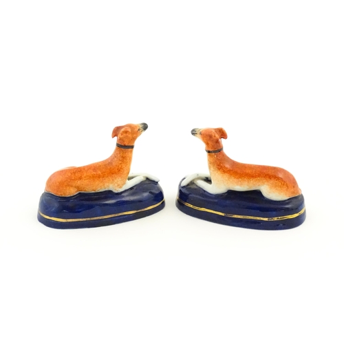 75 - A pair of Staffordshire pottery models of reclining greyhounds / dogs. Approx. 3 1/2