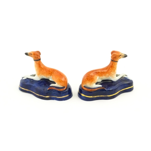 75 - A pair of Staffordshire pottery models of reclining greyhounds / dogs. Approx. 3 1/2