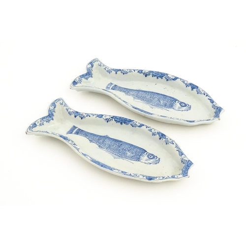 92 - Two Dutch Delft blue and white herring dishes of stylised fish form, with hand painted decoration de... 