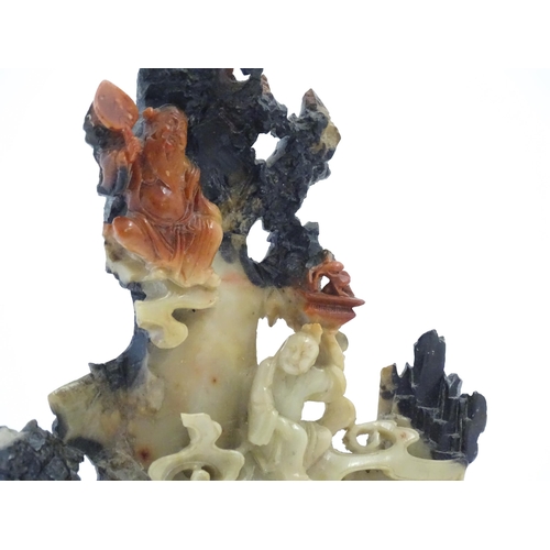 1028 - An Oriental soapstone carving depicting a rocky outcrop with immortal figures amongst clouds. Approx... 