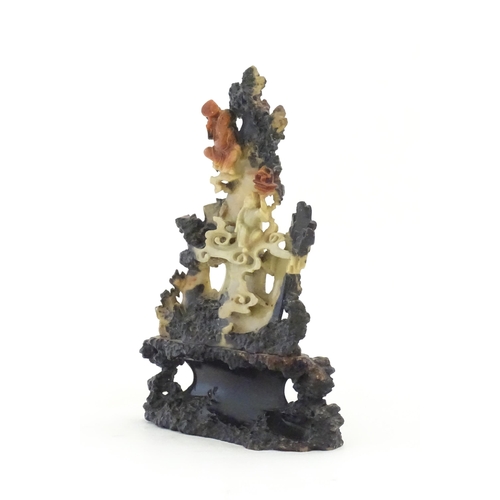 1028 - An Oriental soapstone carving depicting a rocky outcrop with immortal figures amongst clouds. Approx... 