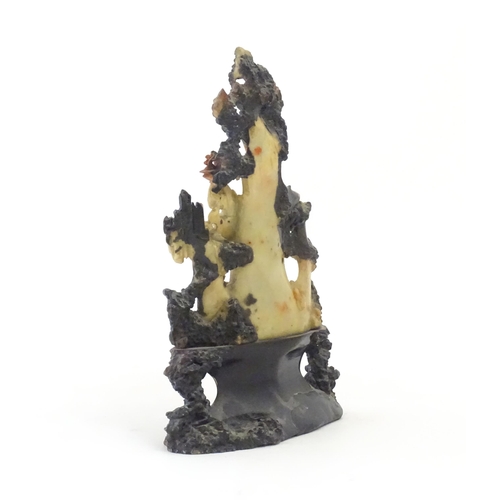 1028 - An Oriental soapstone carving depicting a rocky outcrop with immortal figures amongst clouds. Approx... 