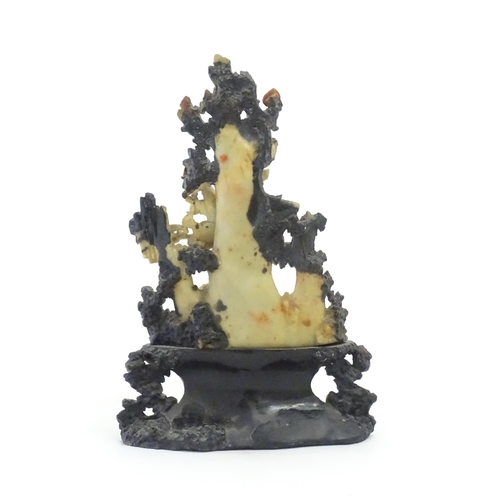 1028 - An Oriental soapstone carving depicting a rocky outcrop with immortal figures amongst clouds. Approx... 