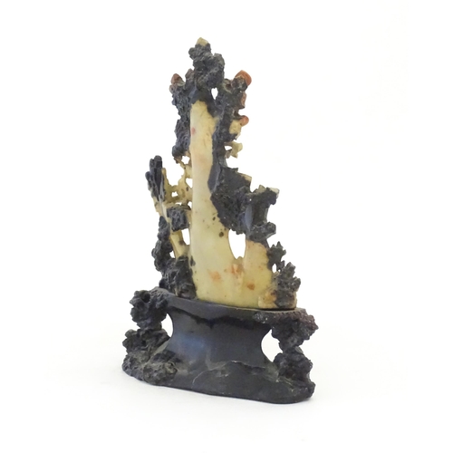 1028 - An Oriental soapstone carving depicting a rocky outcrop with immortal figures amongst clouds. Approx... 