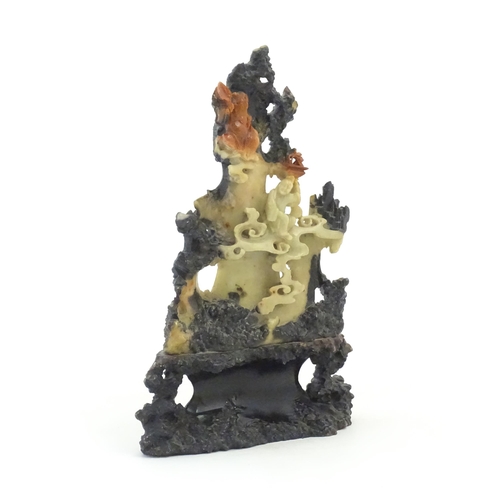 1028 - An Oriental soapstone carving depicting a rocky outcrop with immortal figures amongst clouds. Approx... 