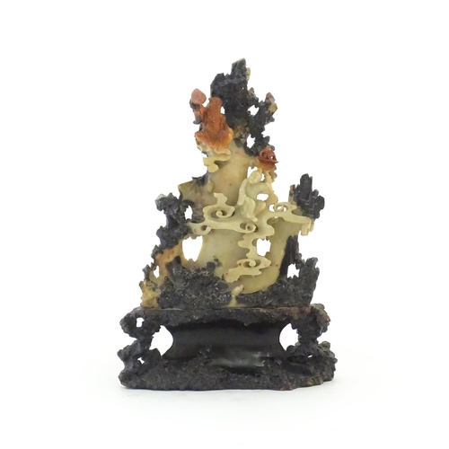 1028 - An Oriental soapstone carving depicting a rocky outcrop with immortal figures amongst clouds. Approx... 