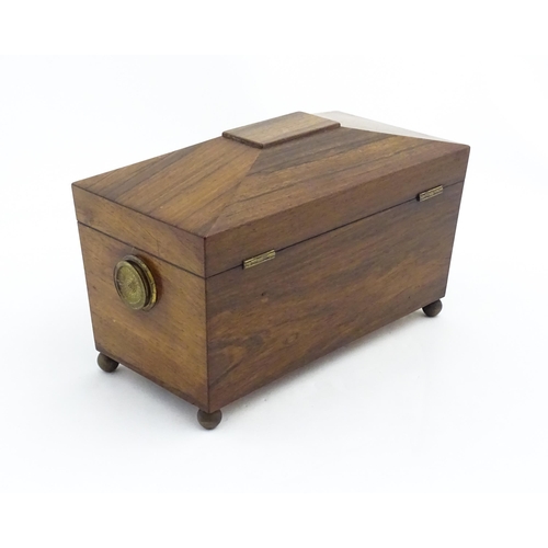 1062 - A 19thC rosewood tea caddy of sarcophagus form with twin roundel handles and ball feet. The interior... 