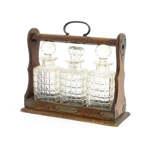 1224 - A 20thC oak tantalus with three glass decanters. Approx. 12