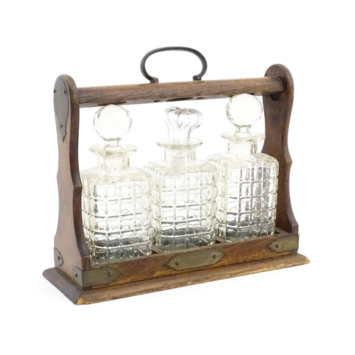 1224 - A 20thC oak tantalus with three glass decanters. Approx. 12