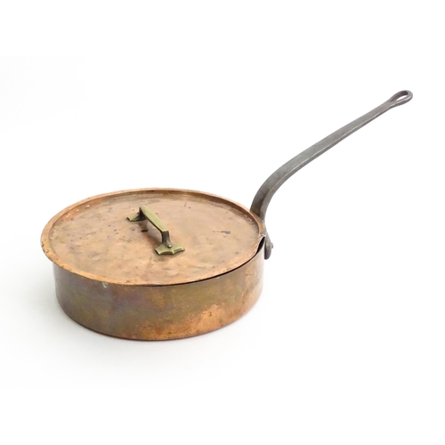 1235 - A large Continental copper saute pan with cast iron handle, the cover with a brass handle. Stamped S... 