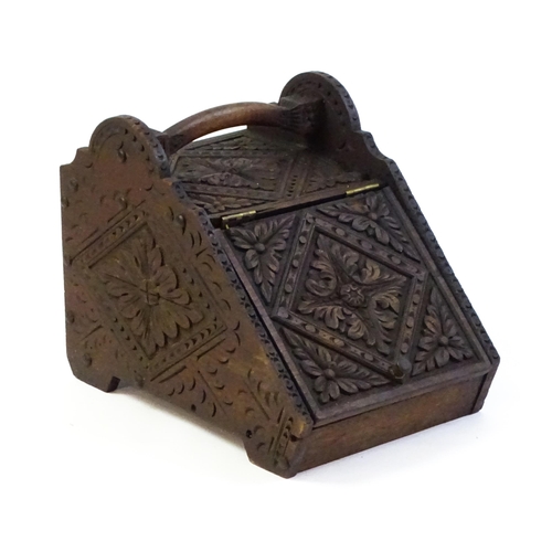 1261 - A 20thC carved coal scuttle with a shaped handle above a floral carved front and sides with lozenge ... 