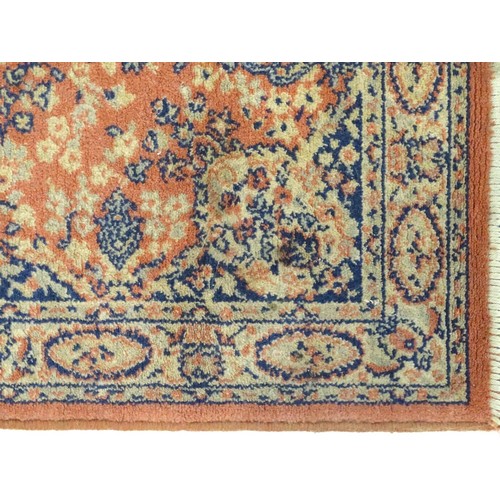 1286 - Carpet / Rug : An orange red ground rug with central medallions and floral detail. Approx 61