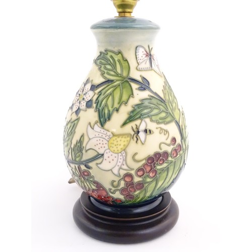 1318 - A Moorcroft table lamp base decorated in the Strawberry Plant and Butterfly pattern, on a turned woo... 