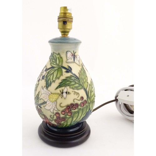 1318 - A Moorcroft table lamp base decorated in the Strawberry Plant and Butterfly pattern, on a turned woo... 