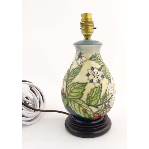 1318 - A Moorcroft table lamp base decorated in the Strawberry Plant and Butterfly pattern, on a turned woo... 