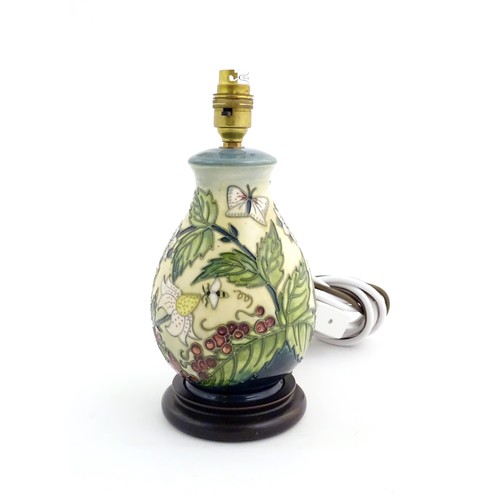 1318 - A Moorcroft table lamp base decorated in the Strawberry Plant and Butterfly pattern, on a turned woo... 