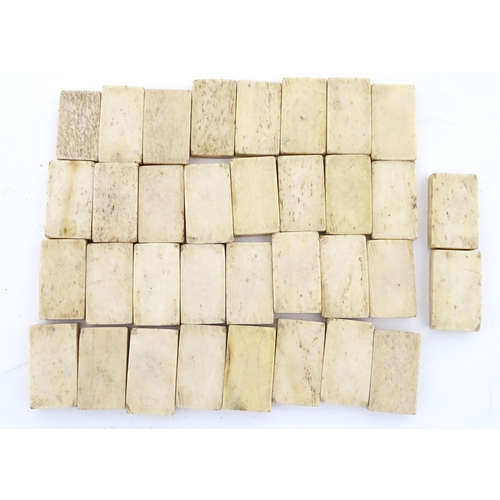 835 - Toys: A quantity of 19thC prisoner of war carved bone dominoes within a wooden box of book form. Dom... 