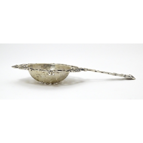 337 - A Continental .835 silver tea / lemon strainer with floral detail to handle. Approx. 5 1/2