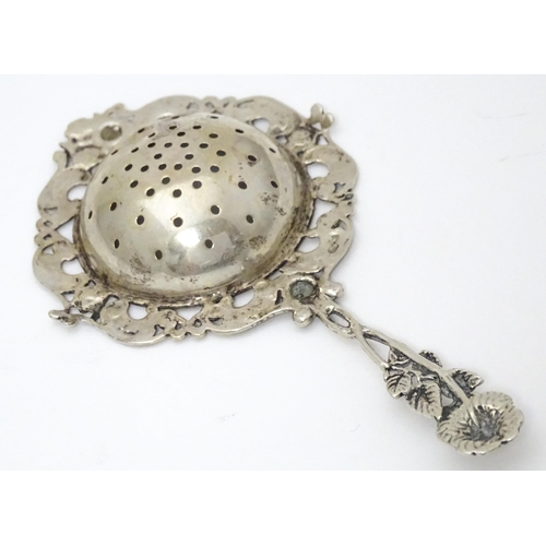 337 - A Continental .835 silver tea / lemon strainer with floral detail to handle. Approx. 5 1/2