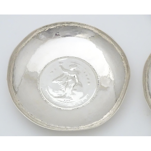 341 - A pair of white metal pin dishes with hammered decoration and inset coin medallions to base. Possibl... 