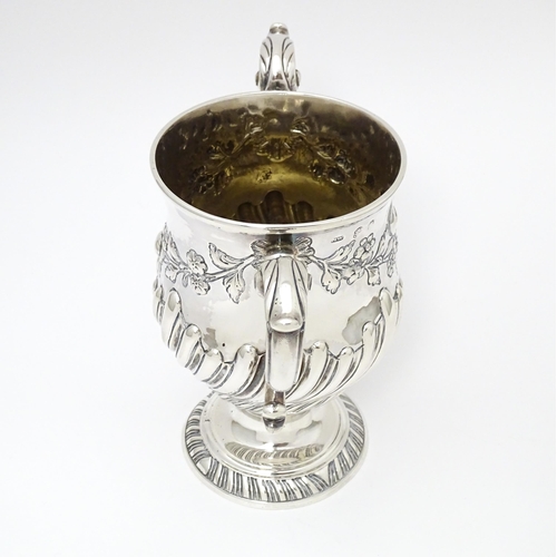 409 - A 19thC Irish silver twin handled pedestal cup with fluted body, and embossed floral and foliate swa... 